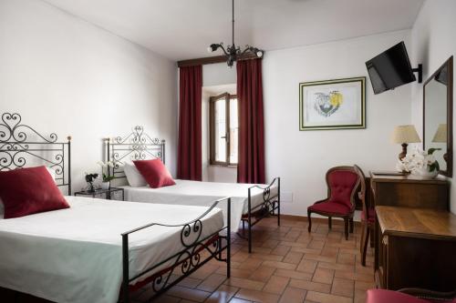 a room with two beds and a desk and chairs at Hotel San Marco in Gubbio