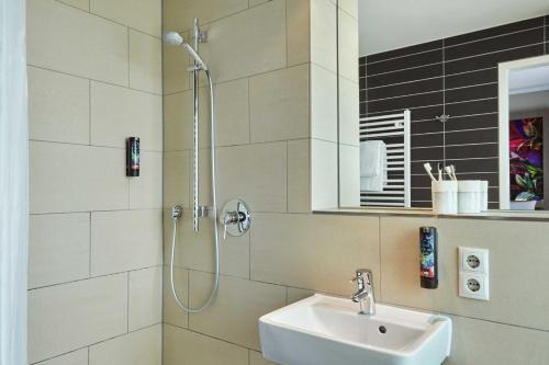 a white bathroom with a sink and a shower at the niu Fusion in Hamburg