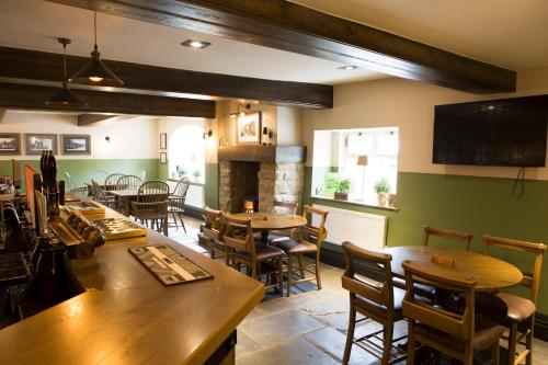 a restaurant with tables and chairs and a fireplace at Square & Compass in Two Dales