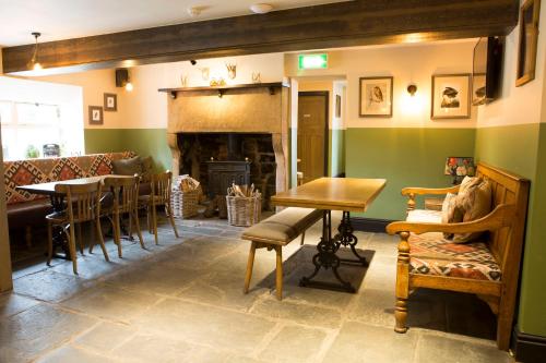 a living room with a fireplace and a table and chairs at Square & Compass in Two Dales
