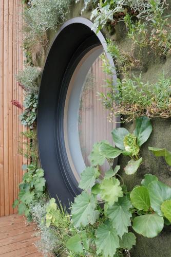 a black circular mirror on a wall with plants at Grand Pension Franziska - inkl CrossFit Gym in Saalbach Hinterglemm