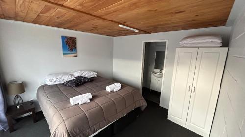 a bedroom with a bed with two towels on it at Butlers Reef Accommodation in Oakura