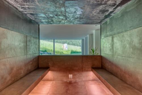 Cette chambre dispose d'une grande fenêtre et de murs en béton. dans l'établissement Hotel Cevedale, à Sulden