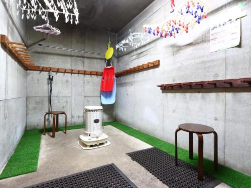 a room with two stools and a stove at Pension Alps Hakuba in Hakuba