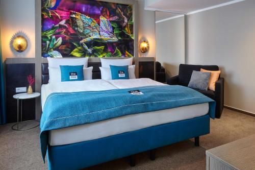 a bedroom with a blue bed with a painting on the wall at the niu Fusion in Hamburg