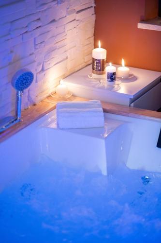 a bathroom with a bath tub with candles and towels at B&B Golden House & spa in Rose