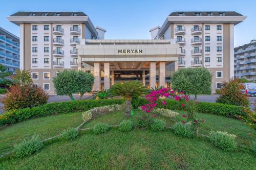 a hotel with a garden in front of a building at Meryan Hotel - Ultra All Inclusive in Okurcalar
