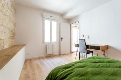 ein weißes Schlafzimmer mit einem Schreibtisch und einem Bett in der Unterkunft Joli appartement avec jardin / Vieux-Lormont in Lormont