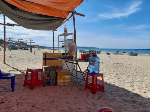 a tent on the beach with a table and two stools at HomeStay Ông Vinh 