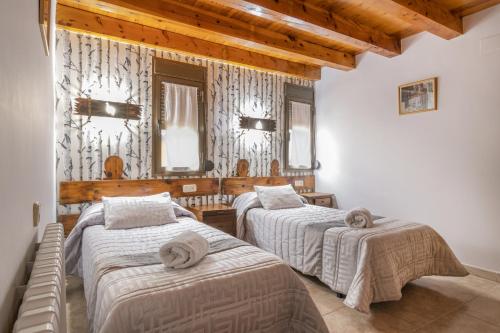 Duas camas num quarto com tectos em madeira em Casa Batlle Ginebro em Les Iglésies