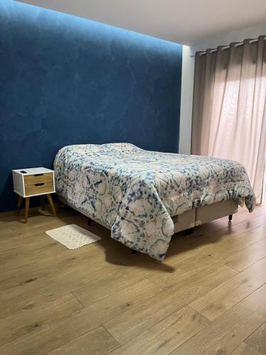 um quarto com uma cama e uma parede azul em Villa Regina em Pato Branco