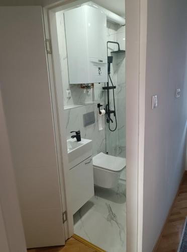 a white bathroom with a toilet and a sink at Apartman Nodi in Sarajevo