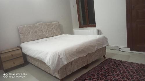 a bedroom with a white bed and a rug at Hamza malikhane (hane) in Trabzon