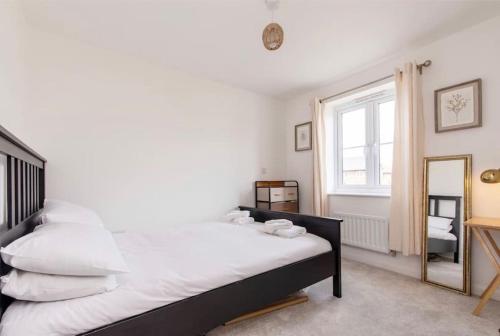 een slaapkamer met een bed met witte lakens en een spiegel bij Charming 2 Bed Home in Edwalton in Nottingham