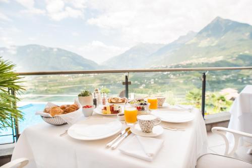 een tafel met ontbijtproducten en uitzicht op de bergen bij Hotel Resmairhof in Schenna