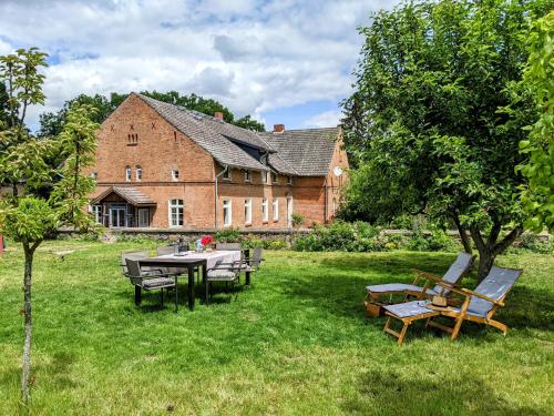 a garden with a table and chairs in front of a building at Ferienloft Himmelblau im 1870 Uckermark in Kröchlendorf