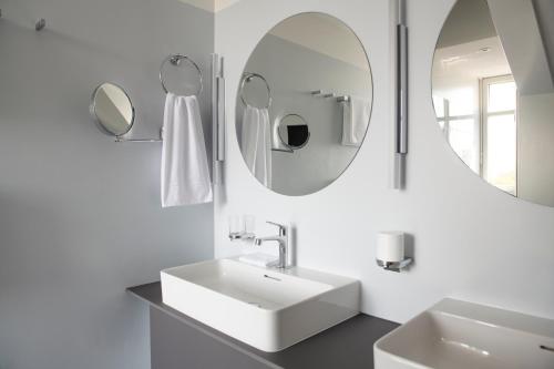 a white bathroom with a sink and two mirrors at Hotel Schützen Rheinfelden in Rheinfelden