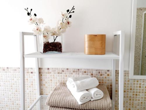 a bathroom with a shelf with towels and flowers at Casa Ida in Pesaro