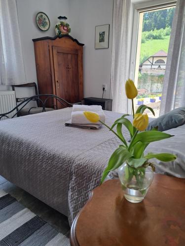 a bedroom with a bed and a vase with yellow flowers on a table at Podgórska Odskocznia in Sokolec