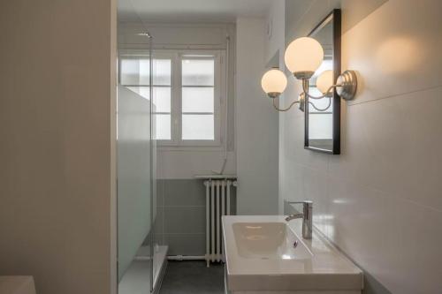uma casa de banho com um lavatório, um espelho e uma janela em Le Chancelier *T2* em Orléans