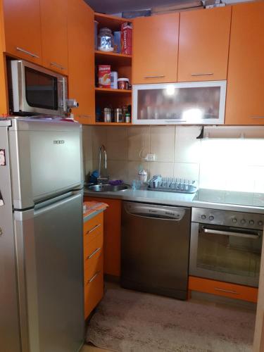 a kitchen with orange cabinets and a stainless steel refrigerator at Apartman Batuta in Budva