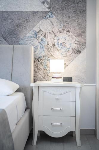 a bedroom with a white nightstand next to a bed at B&B Golden House & spa in Rose
