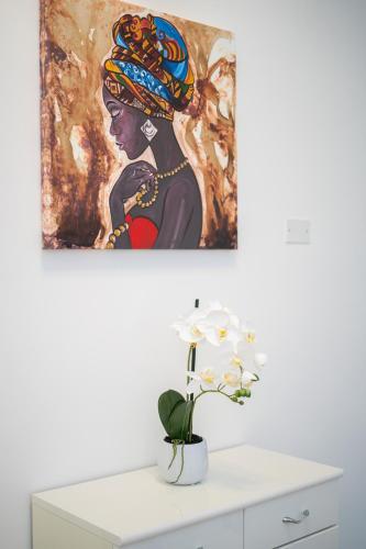 a painting on a wall above a white dresser with a flower at B&B Golden House & spa in Rose