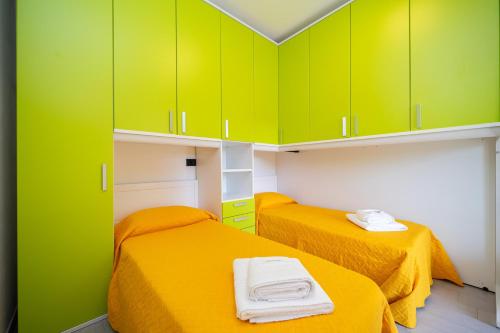 two beds in a room with green cabinets at B&B Golden House & spa in Rose