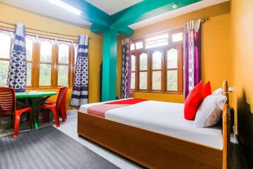 a bedroom with a bed and a table and windows at Flagship Jwajalapa Homestay in Kalimpong