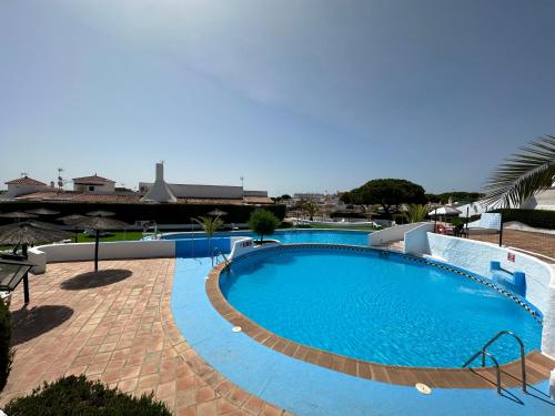 a large swimming pool in a resort with an umbrella at Residencial Macarena in Matalascañas
