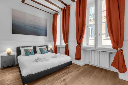 1 dormitorio con 1 cama con cortinas de color naranja en Lucena - Charmant appt en centre-ville, en Toulouse