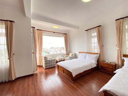 a bedroom with a bed and a large window at Villa Minh Tuyet Dalat in Da Lat