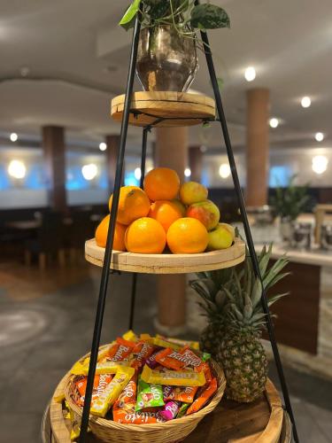 a three tiered fruit stand with a basket of fruit at Hotel Auwirt Zentrum in Saalbach Hinterglemm