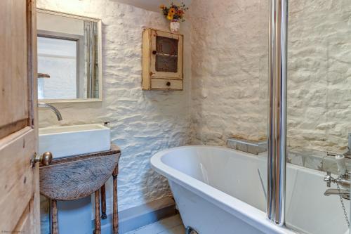 a bathroom with a bath tub and a sink at The Hayloft in Hook Norton