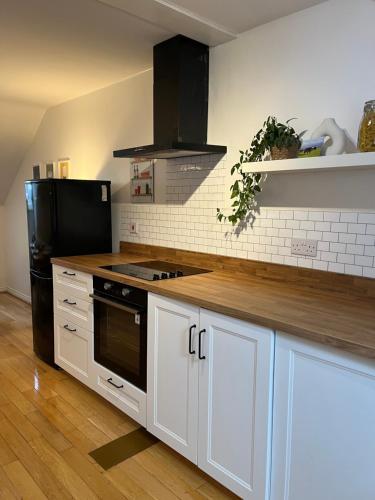 uma cozinha com armários brancos e um frigorífico preto em Homely 2 Story Cathedral City Apartment em Durham