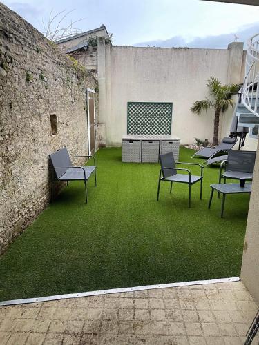 un cortile con sedie e un muro con erba verde di Anselme, F2 duplex avec cour commune et proche de la mer ,2 a Ver-sur-Mer