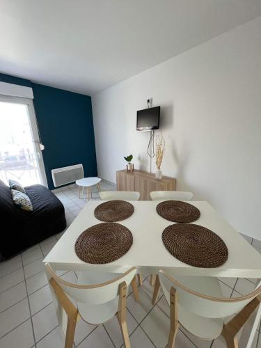 un soggiorno con tavolo e sedie bianchi di Anselme, F2 duplex avec cour commune et proche de la mer ,2 a Ver-sur-Mer