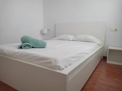 a white bed with a green pillow on it at Ap4Us B1 - Apartment for us - Sightseeing & Beach At The Best Price in Badalona