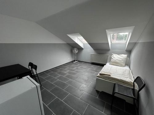 a attic room with a bed and two windows at Boardinghouse Wendelstein in Wendelstein