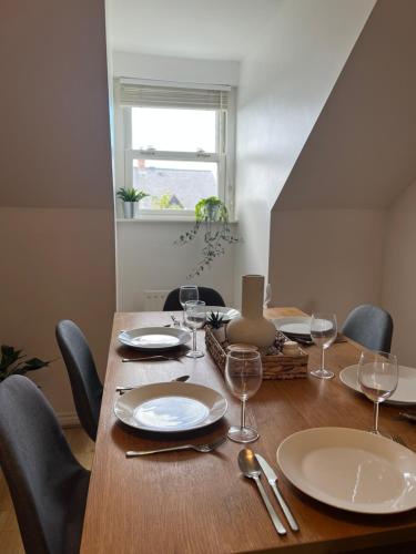 a wooden table with chairs and plates and wine glasses at Homely 2 Story Cathedral City Apartment in Durham