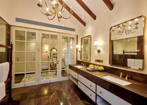 a bathroom with two sinks and a large mirror at amã Stays & Trails Hacienda De Bastora, Goa in Old Goa