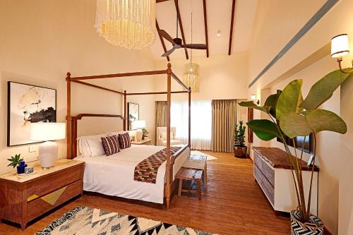 a bedroom with a canopy bed and a potted plant at amã Stays & Trails Hacienda De Bastora, Goa in Old Goa