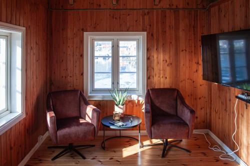 two chairs and a table in a room with wooden walls at Authentic central located cabin close to Reinebringen Lofoten in Reine
