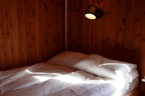 a bed with white sheets in a room with wooden walls at Authentic central located cabin close to Reinebringen Lofoten in Reine
