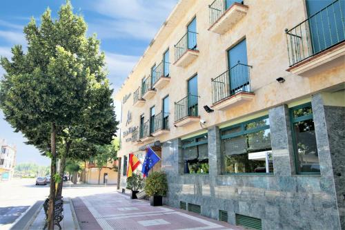 un edificio en una calle con un árbol al lado en Hotel Ele Puente Romano de Salamanca en Salamanca