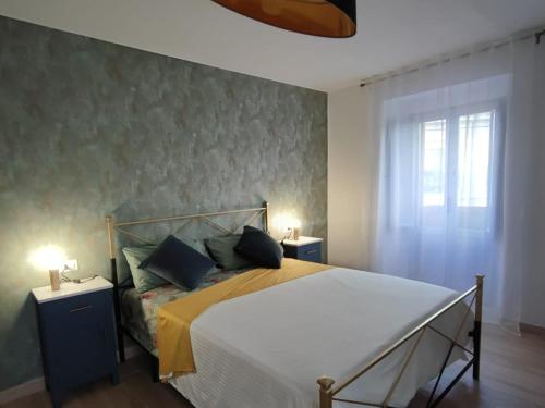 a bedroom with a bed with blue pillows and a window at la casa dei nonni in Musellaro