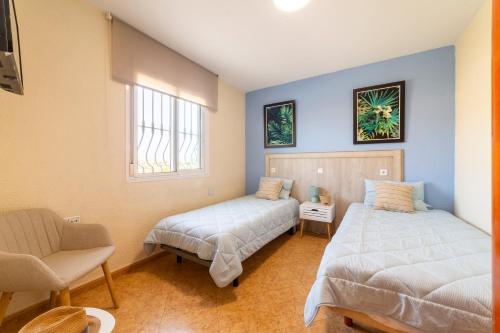 a bedroom with two beds and a chair at Villa Mansa in Pechina