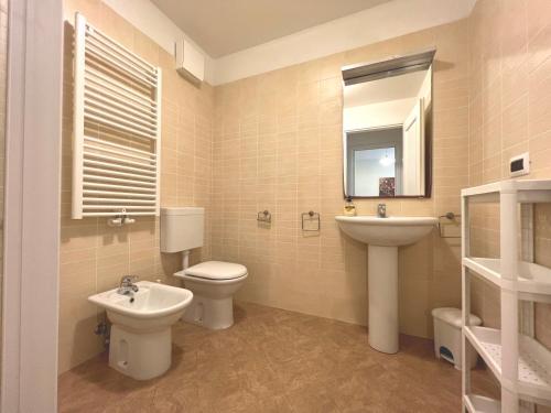 a bathroom with a sink and a toilet and a mirror at Costa Azzurra Apartment in Grado