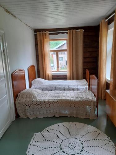 twee bedden in een kamer met een raam en een tapijt bij Cozy cottage by the lake in Lohja