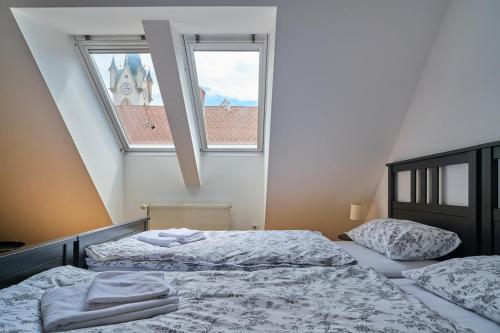 two beds in a bedroom with two windows at Samostan Mekinje in Kamnik